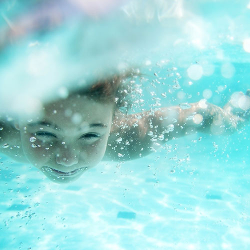 A photo of a child swimming underwater at a swimming lesson