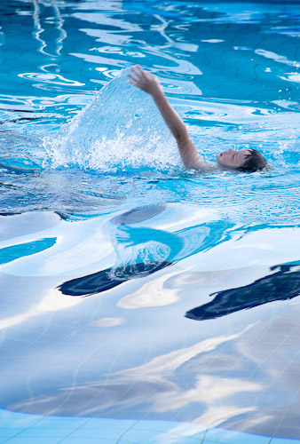 A image of a boy swimming the back-stroke in a school pool