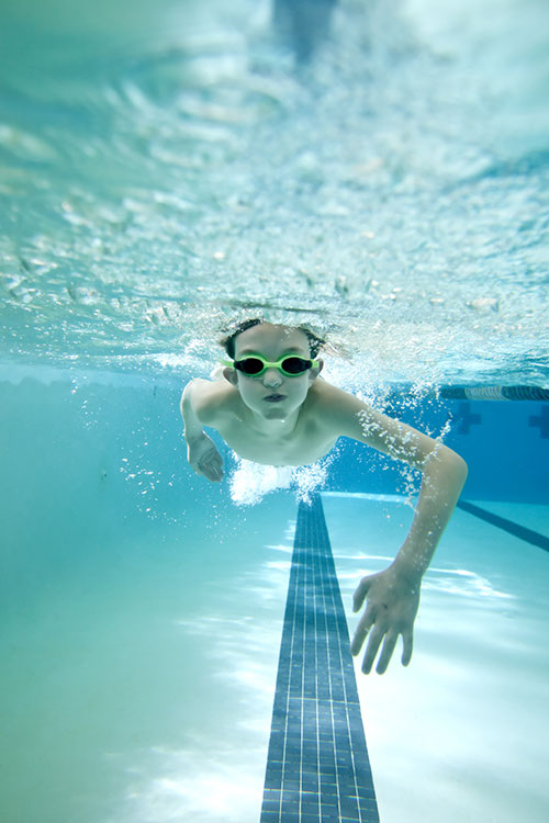 photo of boy swimming underwater and holding his breath